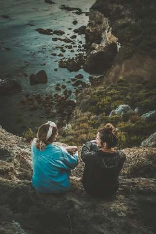 two people talking on a cliff